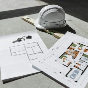 Architectural floor plans with helmet and keys on sunlit floor, perfect for real estate or construction themes.